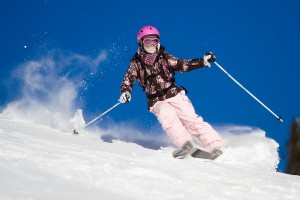 Girl riding on skis with bright blue sky on the background